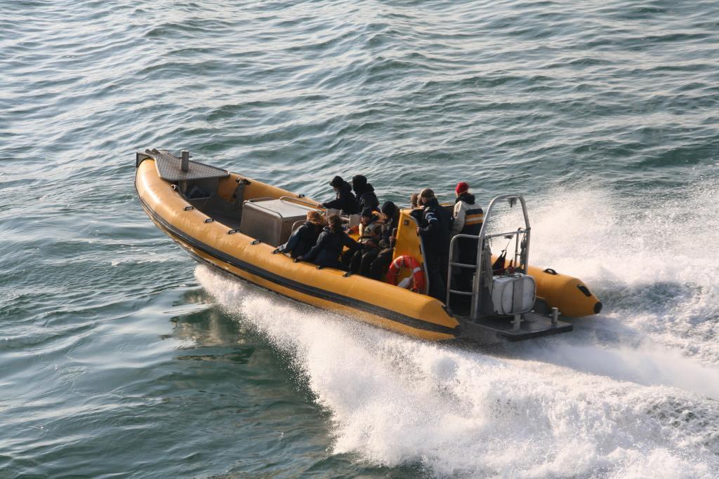 Yellow inflatable speedboat with passengers creating splashes on the water