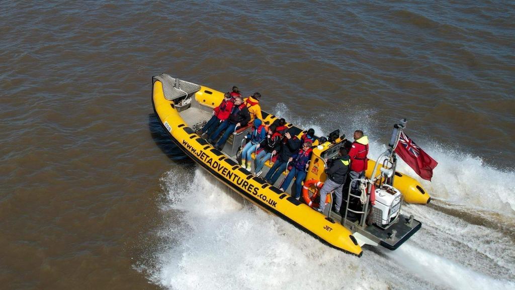 Yellow speedboat with passengers wearing life jackets, operated by a crew with red flag.