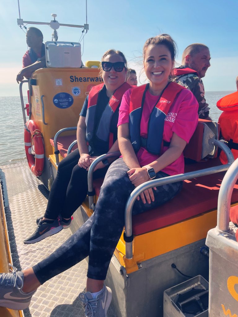 People on a boat wearing life jackets in sunny weather.