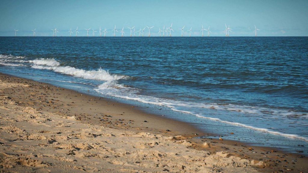 Expansive sandy beaches and dunes along the Norfolk Coast. Wind Turbines in background.